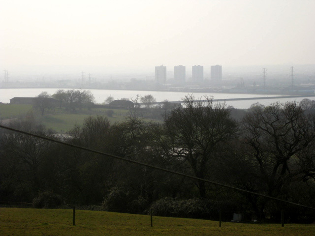 We cross meadowland and scale the Sewardstone Hills to achieve this view of the vast King George's Reservoir. The four tower blocks mark the Alma Road estate in Ponders End. 