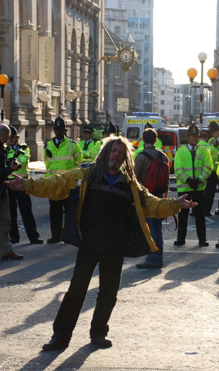 A protester does a little dance for the camera while police look on / image by Doilum 