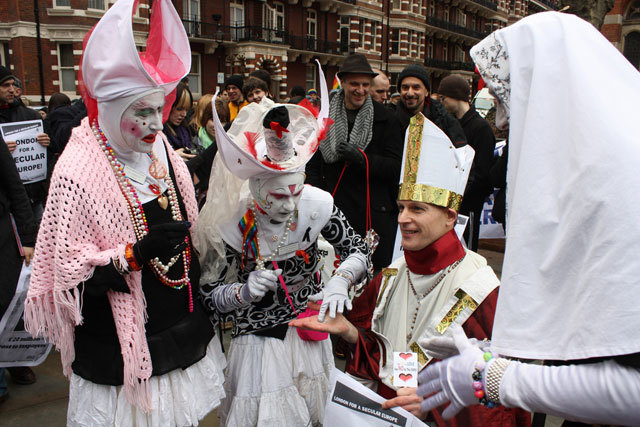 Sisters of the London House of Common Sluts of the Sister of Perpetual Indulgence officiate on a disguised protestor.