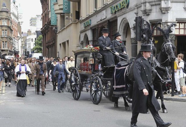 Horse drawn coffin passing Trocadero, causing people to stop and stare