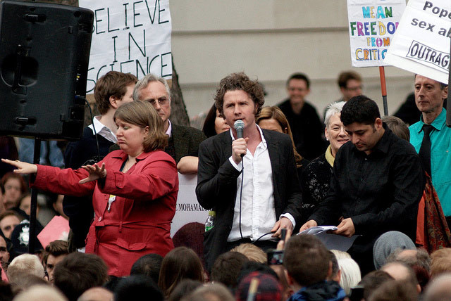 Ben Goldacre, with Richard Dawkins, Johann Hari and Peter Tatchell in the background, and a woman apparently conducting a sÃ©ance. Photo / Joe Dunckley