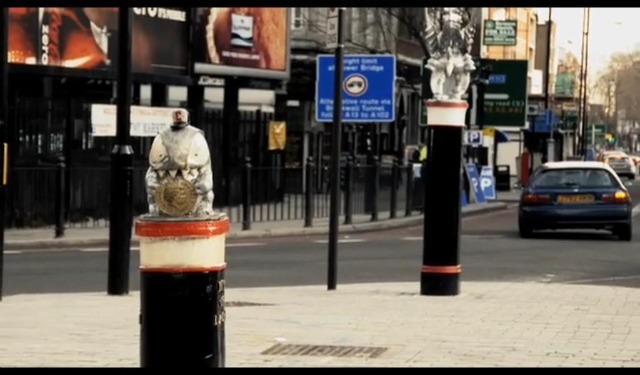 A Credit Crunch Monster at Aldgate is eyed up by one of the City's traditional guardians.