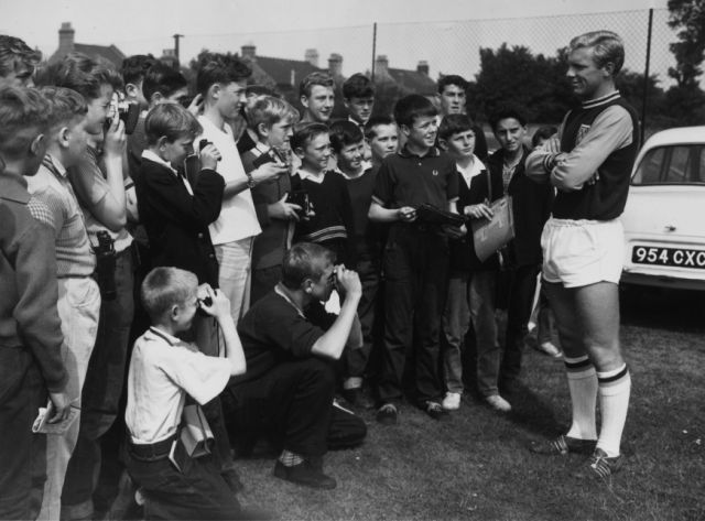Bobby's Fans: 1 August 1962: West Ham and England captain, Bobby Moore, being photographed by young fans during a break in a training session (Photo by Douglas Miller/Keystone/Getty Images) 