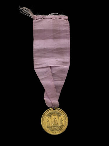 Commemorative medal: Royal Dramatic College; gilt-metal; pierced for suspension; pink ribbon attached; obverse: view of long building; legend; reverse: three Gothic arches; Shakespeare crowned; woman carrying child; aged man; foliate scrolls, © The Trustees of the British Museum