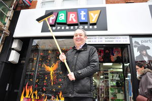 Duncan Mundell celebrates with a broom now his store has reopened almost two years after it was burned during the riots