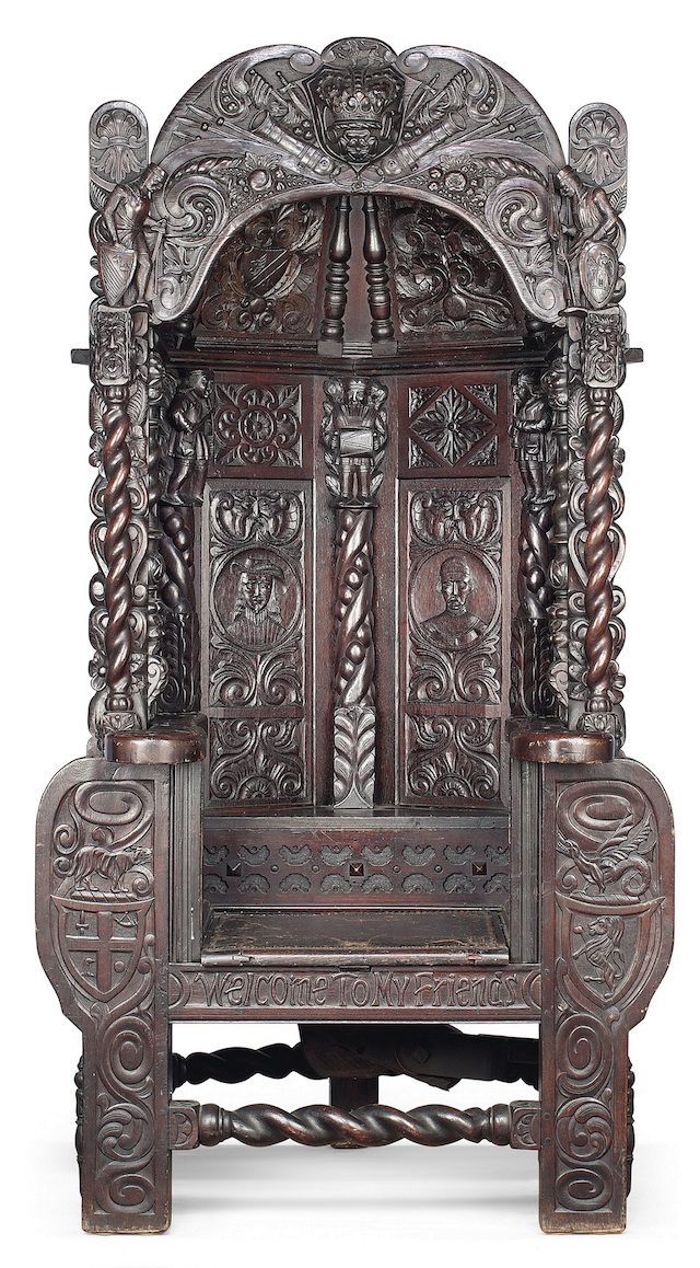 A highly unusual oak 'capture' chair of Elizabethan style, circa 1900.
Its carvings include green man masks, portrait medallions and foliage. The arched canopy has a central boss carved with a Tudor Rose beneath a crown, dated 1603. It is engraved with ‘Welcome to my friends’ carved beneath. When the seat is sat on the 'capture' mechanism is released and a pair of iron bars trap the 'victim' in the chair. There is a concealed release mechanism to rear at base. (Estimate £25,000-£35,000)