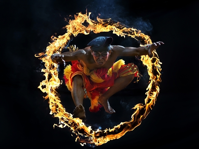 A man jumps through a ring of fire as part of an Indonesian cultural ritual. Copyright Aprison Aprison.