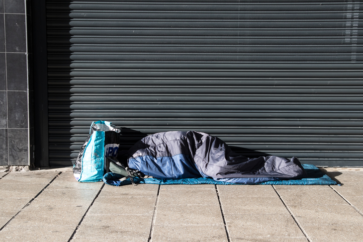 Someone in a sleeping bag outside closed shutters