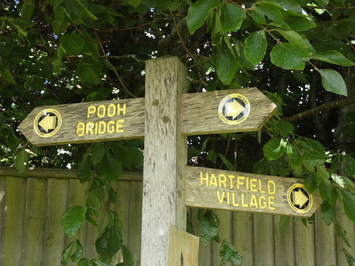 A sign pointing to Pooh Bridge in one direction and Hartfield Village in the other