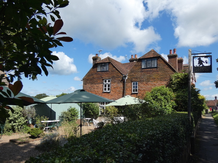 The exterior of Pooh Corner, a traditional cottage-style building with tables and umbrellas in the garden