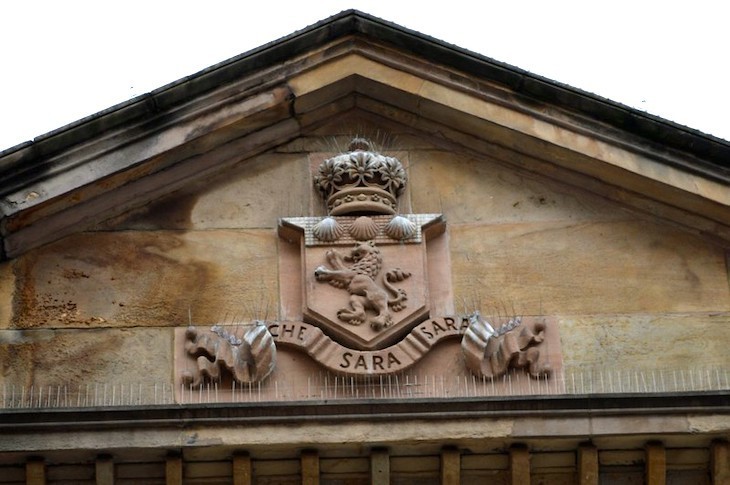 A pediment with a lion-centred coat of arms and the motto che sara sara
