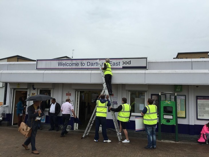 Workers in high-vis change a station name to Dartford East