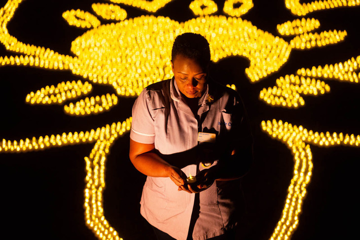 Beth holds an LED tea light, with the thousands of others behind her