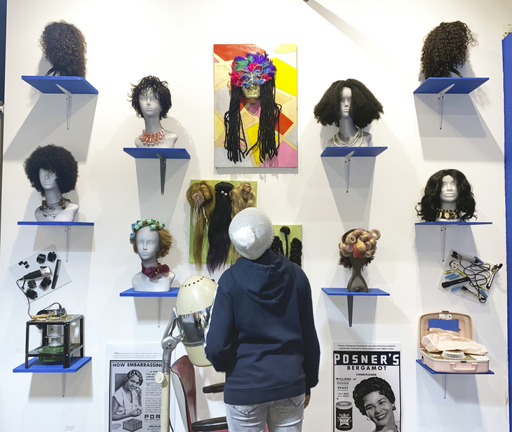 a visitor studying a wall of busts with wigs