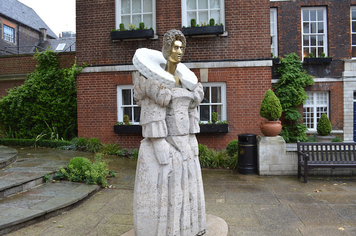 A very strange statue of Elizabeth I. Her chunky body is made from white stone. Her head, supported on a slim neck, is golden. And she appears to have a giant polo mint over her shoulders. All very odd
