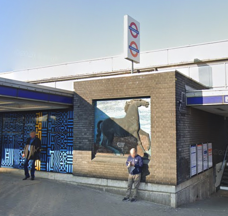 A black horse on a brick wall outside a tube station