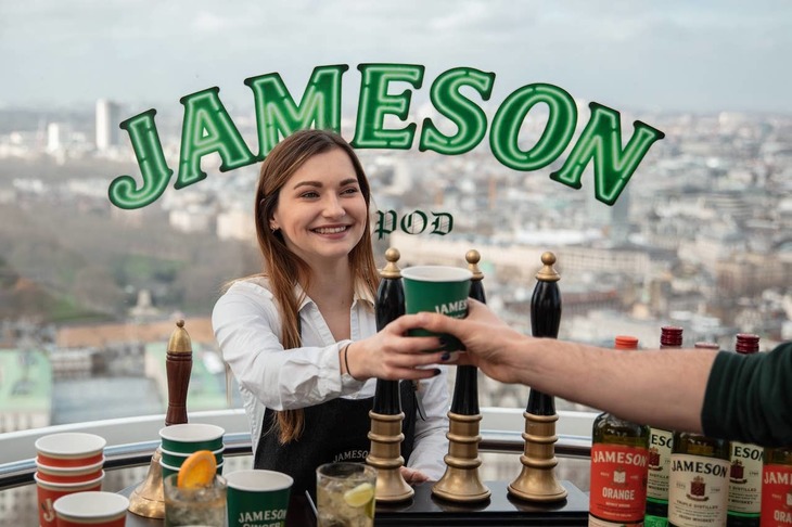 a woman serves a drink from behind a bar in a London Eye pod