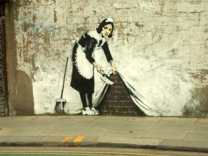 A traditionally dressed maid lifts up part of a wall to sweep things away