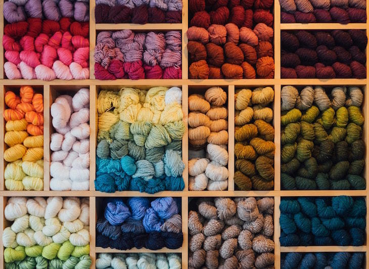 Open shelves, piled high with balls of wool, ordered by colour