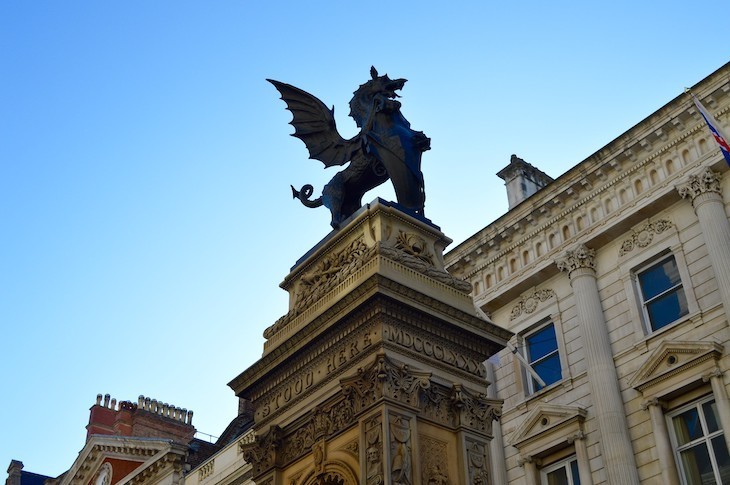 A shield-bearing dragon is silhouetted against a blue sky