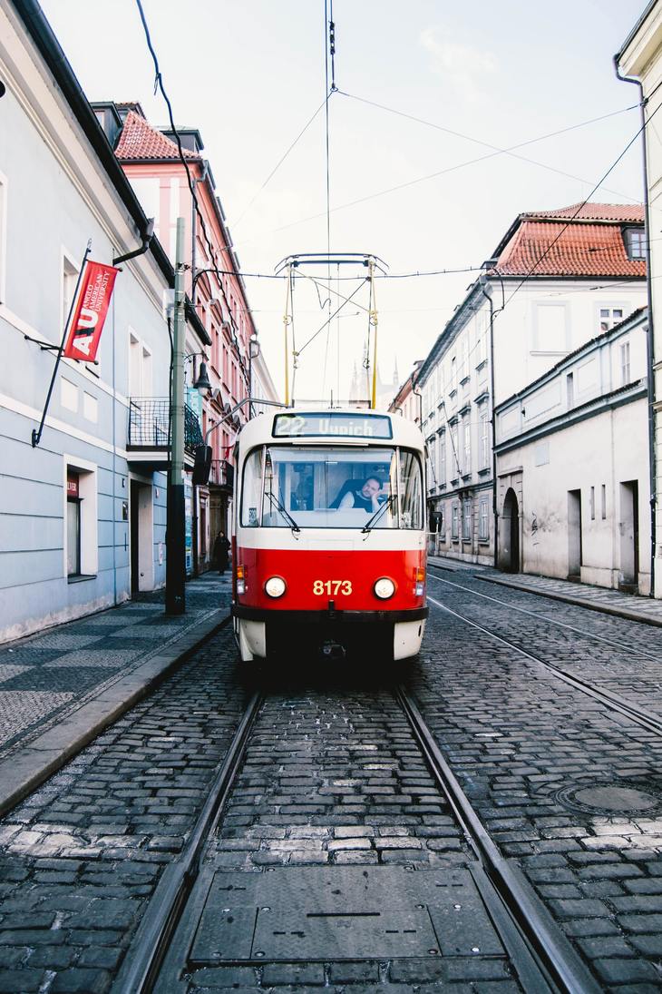 A red and white tram comes for the camera across a cobbled street