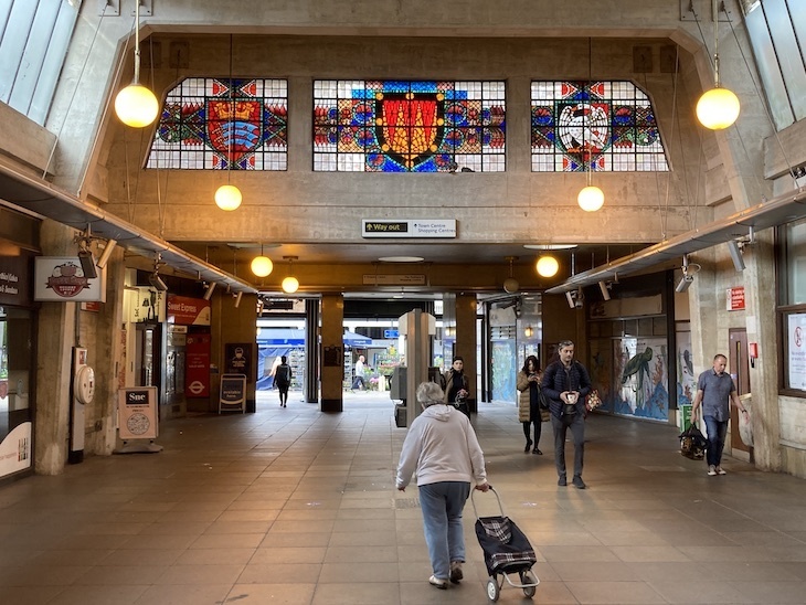 A tube station with stained glass windows at clerestory level and the exit in the distance