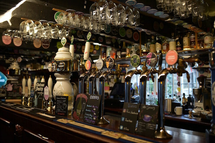 A bar with 12 different beer pumps, and glasses hanging overhead