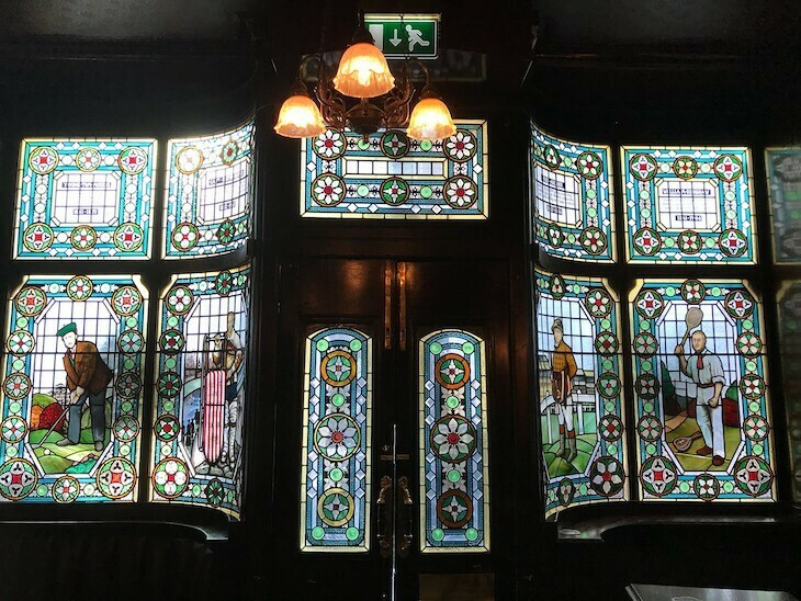 A pub interior whose windows depict sports personalities in stained glass