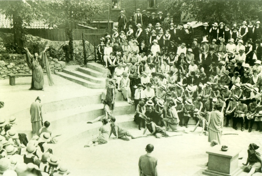Black and white image of people gathered in an amphitheatre, watching a show