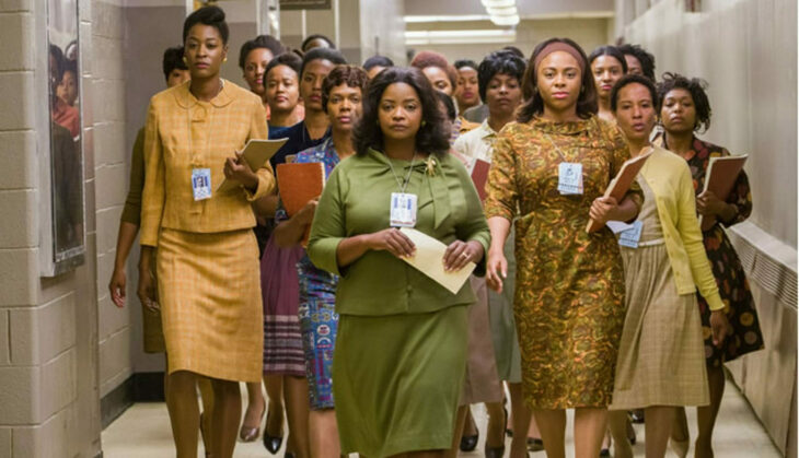 A group of Black women march purposefully down a corridor