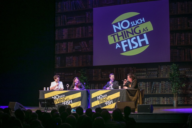 The No Such Thing team on stage, with their logo behind them