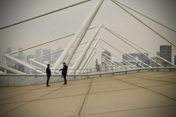 On the roof of Excel, two figures in black stand in the middle distance, engaged in conversation