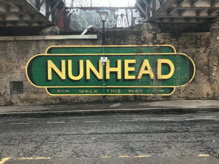 A green and yellow painted sign saying Nunhead