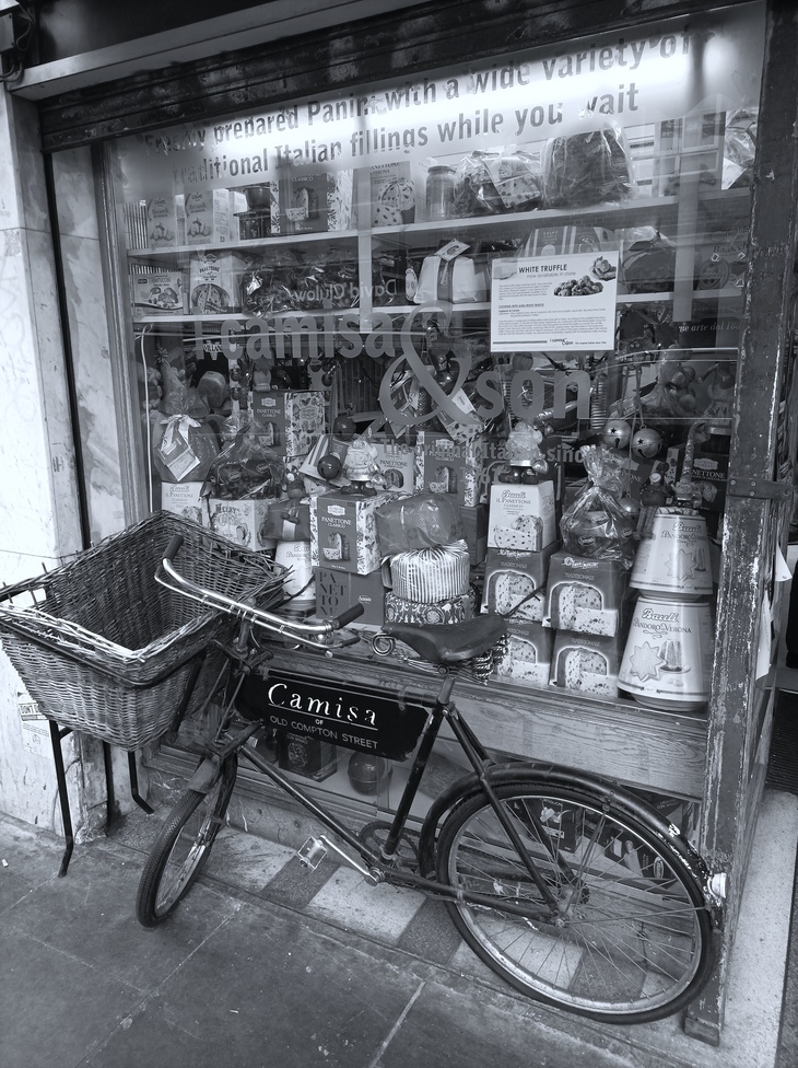 An old basketed bike outside an Italian deli window