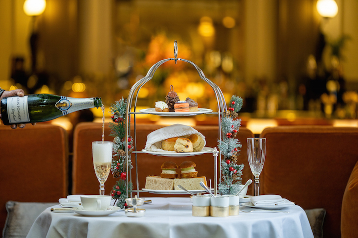 Afternoon tea served on a silver three-tier stand, with champagne being poured