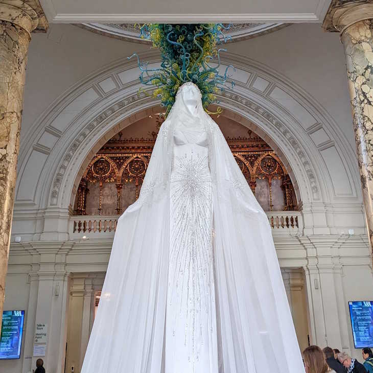 A white statue wearing a long, white veiled dress covered in Swarovski crystals