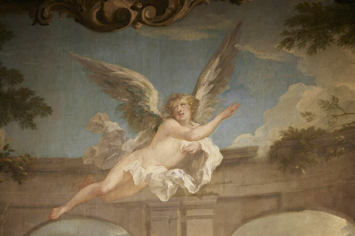 A fresco of an angel reaching to the right where clouds are forming.