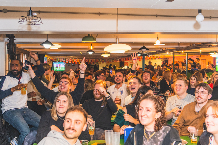 Loads of people rammed into a bar, facing camera