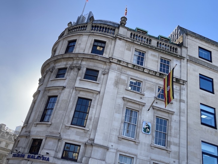 A white stone embassy building with the Ugandan flag