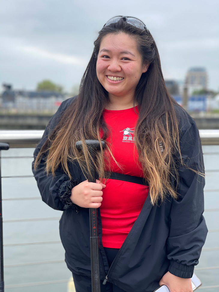 A young woman smiling, holding an oar