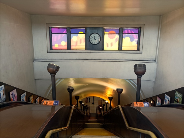 Escalators with uplighters and a vivid artwork above them