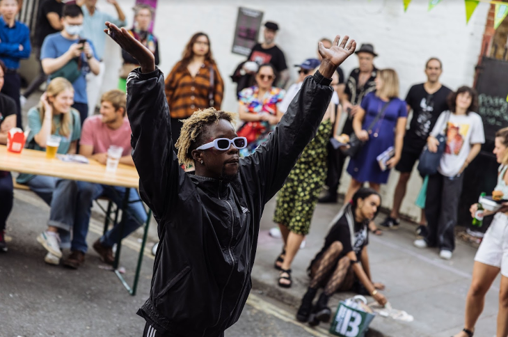 A young person with sunglasses raises their hands in the air