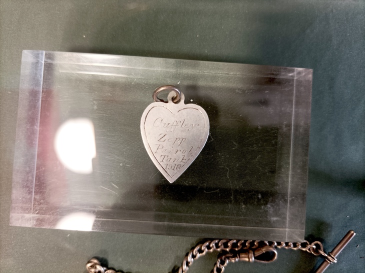 A heart shaped pendant inscribed with writing claiming it's taken from the pedwtrol tank of the downed airship