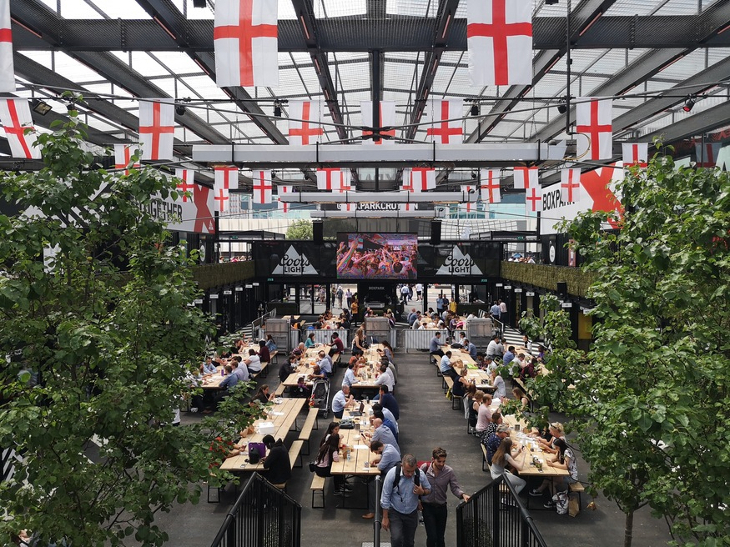 Boxpark with long tables and England flags hanging from the ceiling