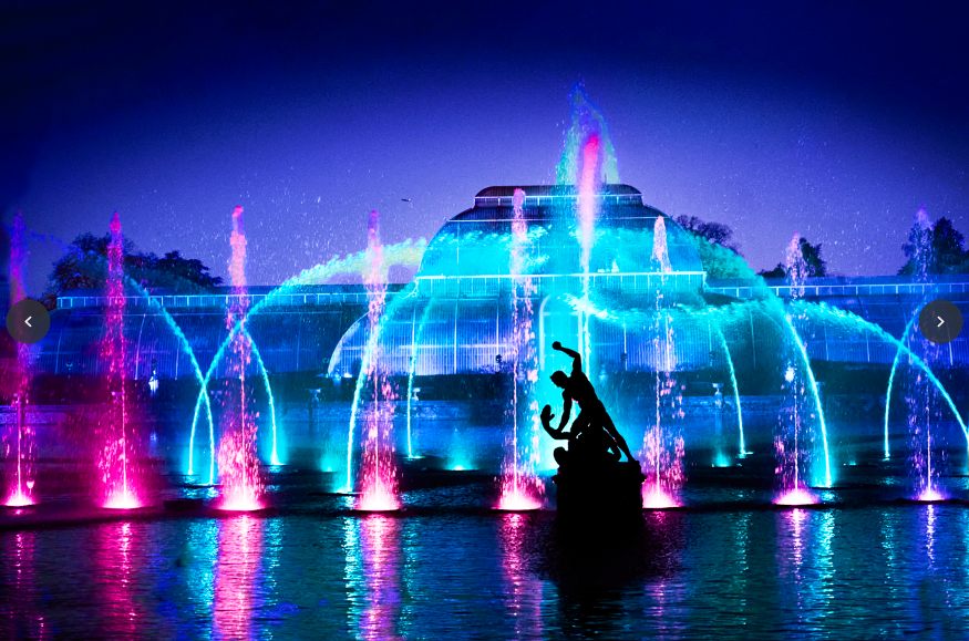 Purple and blue illuminated fountains dancing in front of the Palm house at Kew Gardens 