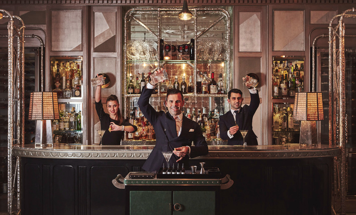 Three Bar staff at a posh bar pouring martinis