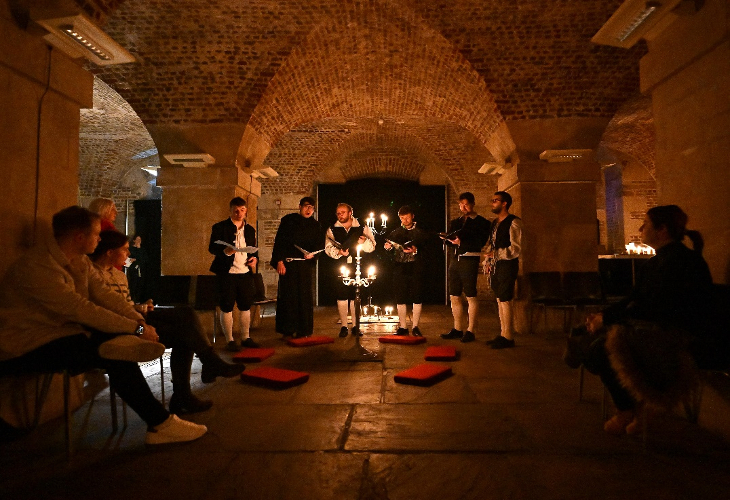 Musicians performing in a crypt lit by candles