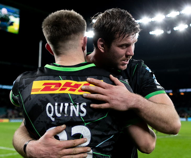 Two rugby players in Harlequins kit embracing and lapping each other on the back