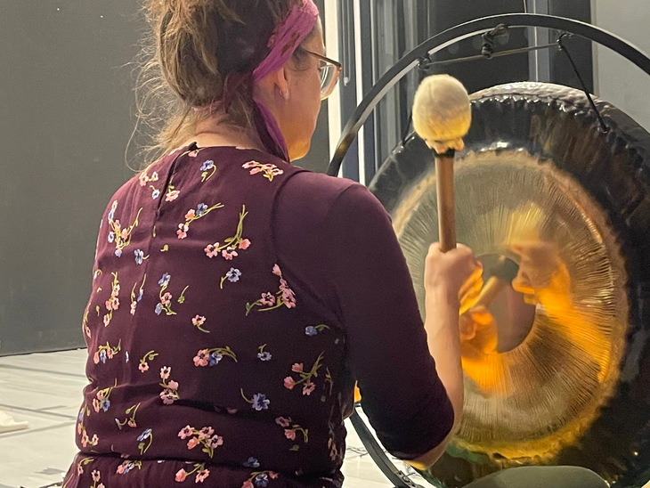 A woman hitting a gong