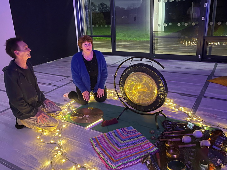A man and woman kneeling in front of a gong